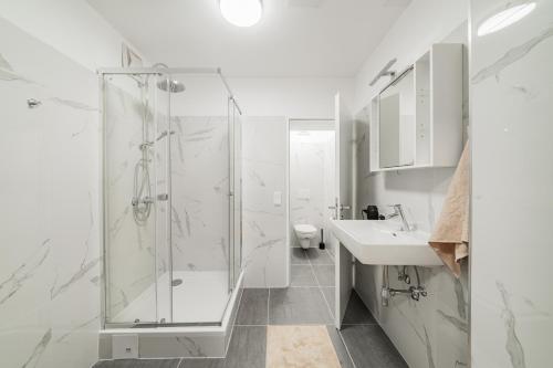 a white bathroom with a shower and a sink at Modern Central City Rooms in Vienna