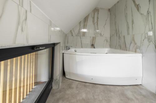 a white bath tub in a bathroom with marble walls at Villa Strtenica in the vineyard in Pristava pri Mestinju