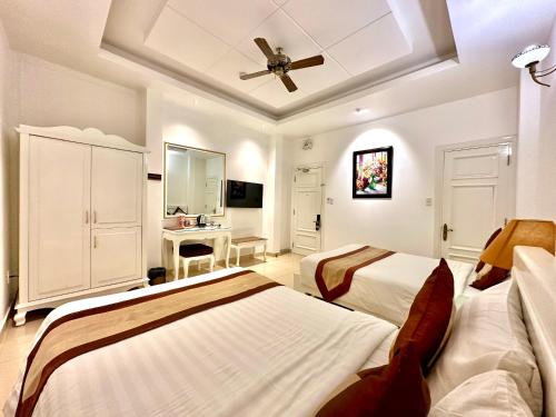 a bedroom with two beds and a ceiling fan at Tulip Hotel in Da Lat