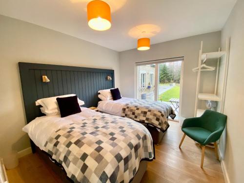 a bedroom with two beds and a green chair at The Lodge at Muir Estate in Thornhill