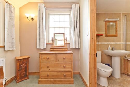 La salle de bains est pourvue d'un lavabo, de toilettes et d'un miroir sur une commode. dans l'établissement Bridge Cottages Bridge House, Old Post, Bridge Suite, Sleeps 16, à Coniston