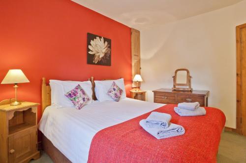 - une chambre avec un lit blanc et un mur rouge dans l'établissement Bridge Cottages Bridge House, Old Post, Bridge Suite, Sleeps 16, à Coniston