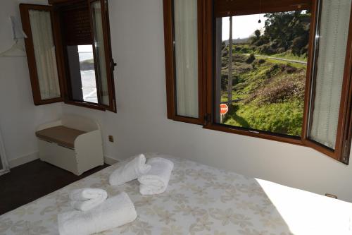 a bedroom with a bed with towels and a window at Lighthouse Perlora vacaciones en el mar in Perlora