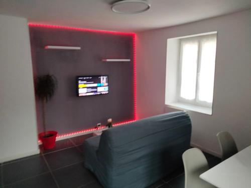 Agréable appartement في موربييه: غرفة معيشة مع أريكة وأضواء حمراء