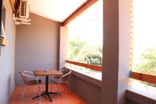 una mesa pequeña y 2 sillas en un balcón con ventana en Casa De Jardim Guesthouse, en Centurion