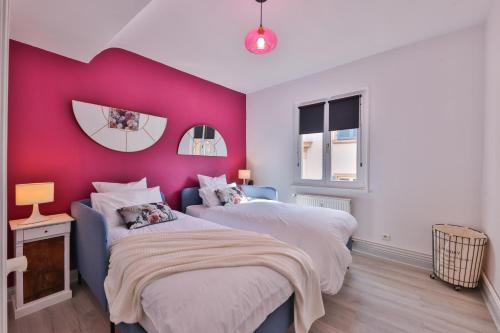 - 2 lits dans une chambre avec un mur rose dans l'établissement Le Moderne Vintage Hyper Centre, vue cigognes, montagne, neuf au calme, 3 étoiles, à Munster