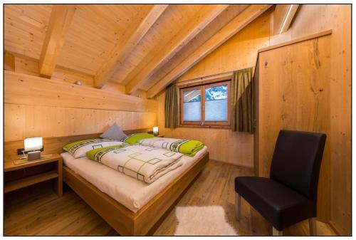 a bedroom in a log cabin with a bed and a chair at Ferienchalet Elisabeth in Steeg