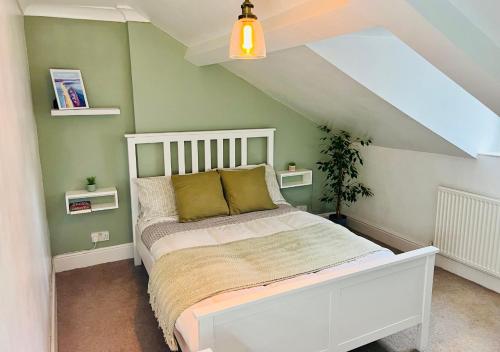 a bedroom with a white bed with green walls at Top Floor Apartment Overlooking Torquay Harbour Pet Friendly in Torquay