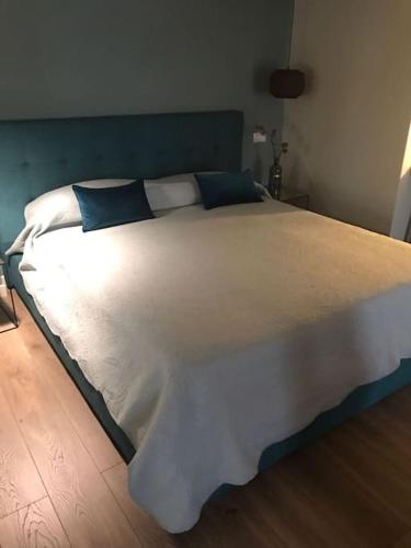a large white bed with blue pillows on it at Maisonette in Vigevano