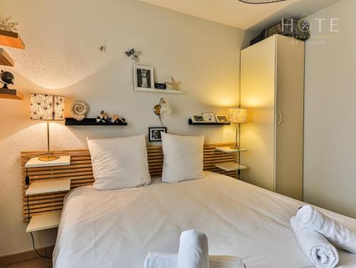um quarto com uma grande cama branca e 2 almofadas em Maison avec piscine résidence vacance em Saint-Jean-dʼOrbetiers