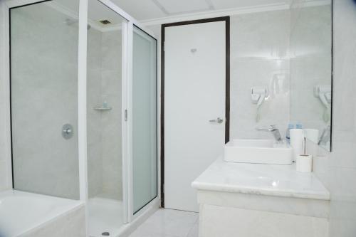 a white bathroom with a sink and a shower at Grand Inna Medan in Medan