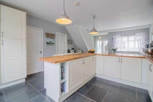 a kitchen with white cabinets and a tile floor at Pear Tree House in Beeston