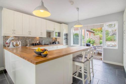 a kitchen with white cabinets and a wooden counter top at Pear Tree House in Beeston