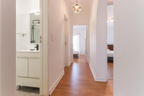 - un couloir blanc avec lavabo et miroir dans l'établissement Oeiras Balcony by Homing, à Oeiras