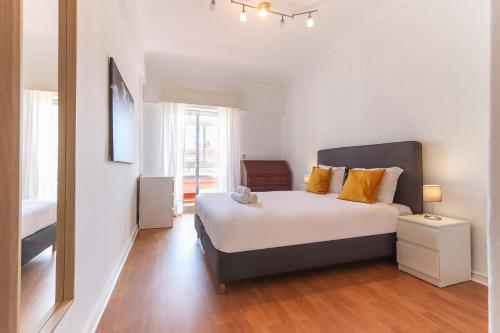 a bedroom with a large bed with yellow pillows at Oeiras Balcony by Hosty in Oeiras