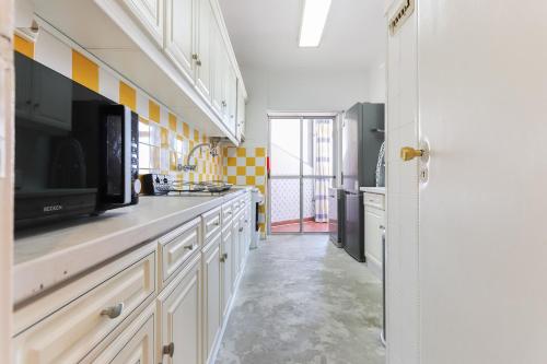a kitchen with white cabinets and a tv on a counter at Oeiras Balcony by Hosty in Oeiras