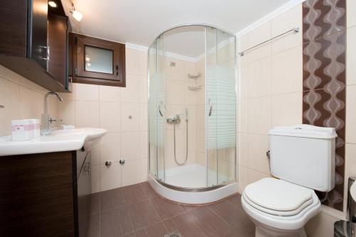 y baño con ducha, aseo y lavamanos. en Vila Mond Sea View Apartments en Kinira