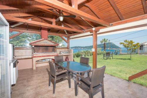 a patio with a table and chairs and a grill at Vila Mond Sea View Apartments in Kinira