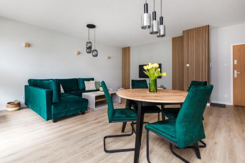 a living room with a table and green chairs at Uroczy ,,Bursztynowy ,, apartament blisko plaży , parking w cenie in Gdańsk