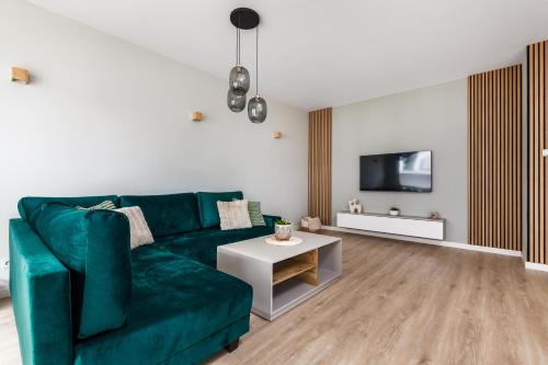 a living room with a green couch and a tv at Uroczy ,,Bursztynowy ,, apartament blisko plaży , parking w cenie in Gdańsk