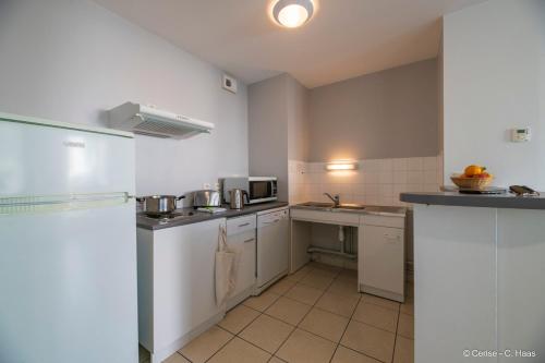 a small kitchen with white cabinets and appliances at Cerise Nantes Atlantis in Saint-Herblain