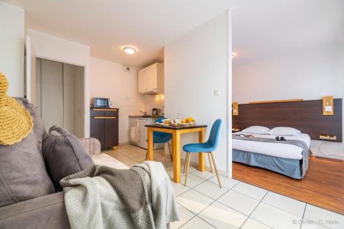 Habitación de hotel con cama, sofá y mesa en Cerise Nantes Atlantis en Saint-Herblain