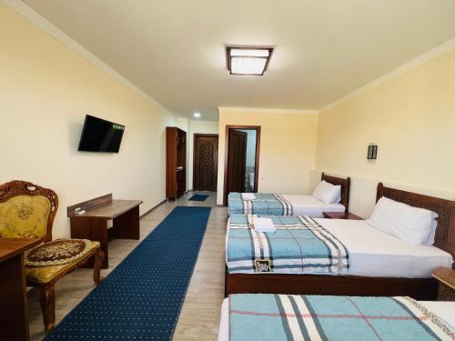 a hotel room with three beds and a tv at 2nd floor in Bukhara