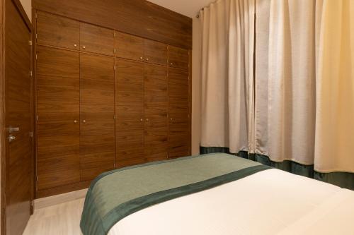 a bedroom with a bed with wooden cabinets and a window at BiBo Suites Real Chancilleria in Granada
