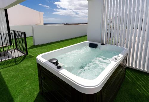 bañera de hidromasaje en un balcón con césped verde en Shambhala Fuerteventura, en Parque Holandes