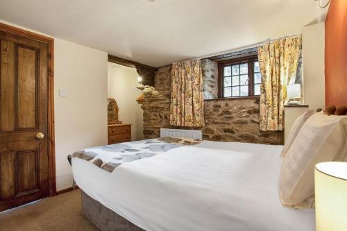 um quarto com uma grande cama branca e uma janela em The Coppermines Mountain Cottages Sawyers, Carpenters, Millrace, Pelton Wheel, Sleeps 22 em Coniston