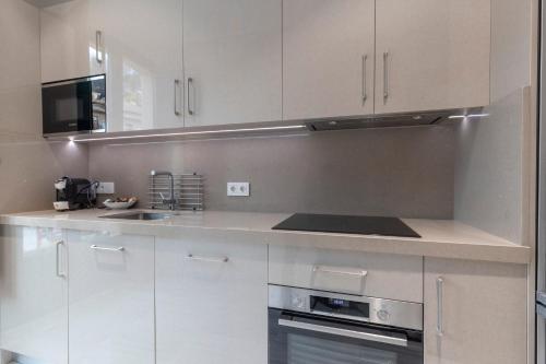 a kitchen with white cabinets and a stove top oven at BiBo Suites Real Chancilleria in Granada