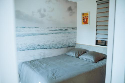 a bed in a room with a painting of the ocean at Martine & Thomas Santa Lucia in Saint-Raphaël