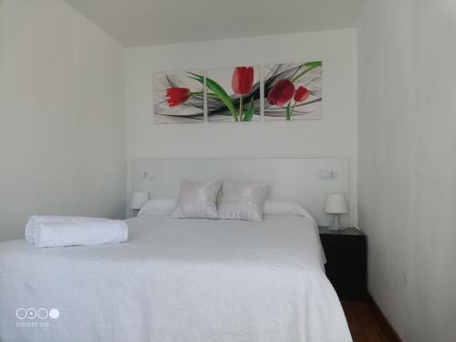 a bedroom with a white bed and a picture of red flowers at VuT Dalia in Avila