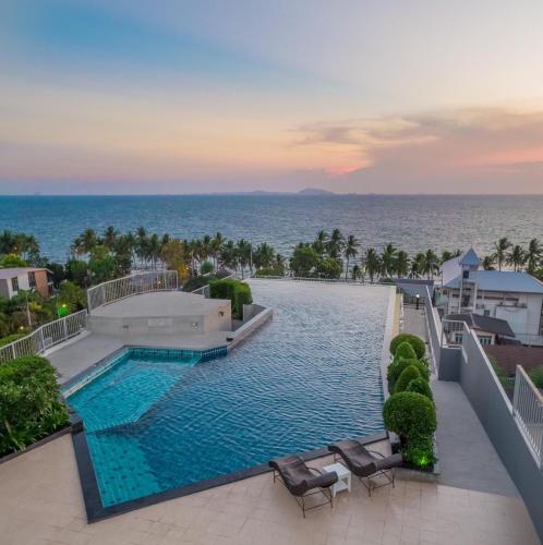 a swimming pool with chairs and the ocean in the background at The Patio bangsaen miracle Seaview in Ban Bang Saen (1)