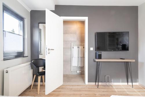 een kamer met een bureau, een televisie en een deur bij Apex Nürburg in Nürburg