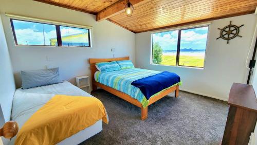 a bedroom with two beds and a window at The Sunrise Bach - One Tree Point Holiday Home in One Tree Point