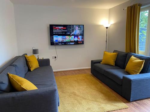 a living room with a blue couch and yellow pillows at Cheerful 4-bedroom house with multiple car parking in Manchester