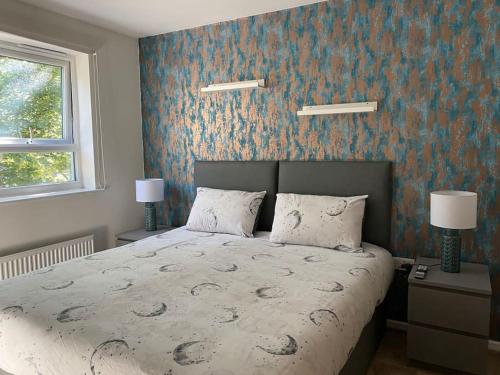a bedroom with a large bed and a blue wall at Cheerful 4-bedroom house with multiple car parking in Manchester