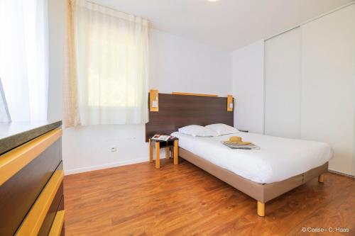 a bedroom with a bed and a wooden floor at Cerise Nantes Atlantis in Saint-Herblain