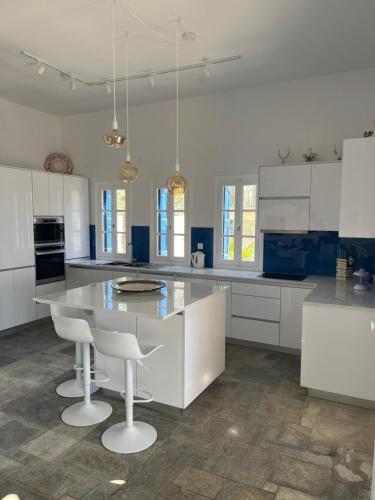 a kitchen with white cabinets and a large island with stools at Kalymnos, très belle villa avec vue sur la mer in Kalymnos