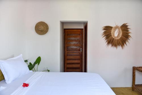 a bedroom with a white bed and a wooden door at Dar Mar Hostel & Coworking in Paje