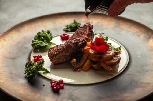 a plate of food with meat and potatoes on it at Villa Ammende Restaurant and Hotel in Pärnu