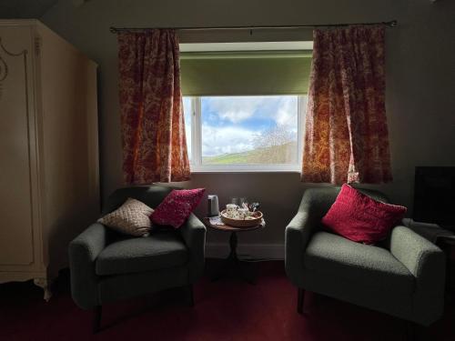 a living room with two chairs and a window at Pentre Cerrig Country House in Llanferres