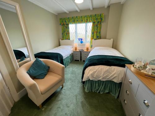 a bedroom with two beds and a chair and a mirror at Pentre Cerrig Country House in Llanferres