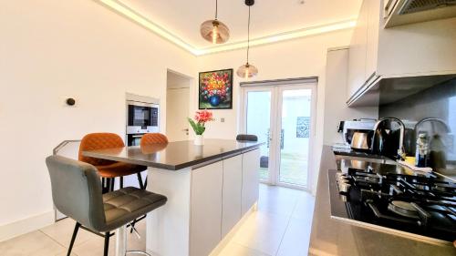 a kitchen with a counter and a table with chairs at Surbiton Luxury Garden House 19 in Surbiton