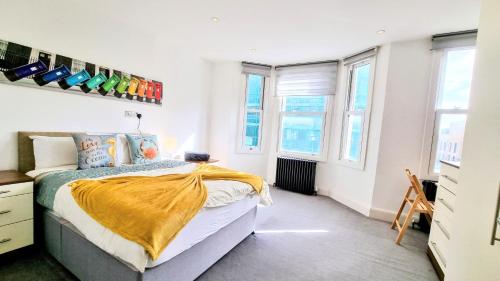 a bedroom with a bed with a yellow blanket on it at Surbiton Luxury Garden House 19 in Surbiton