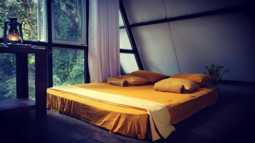 1 dormitorio con 1 cama con sábanas y almohadas amarillas en Riverston Nature Villa, en Rattota