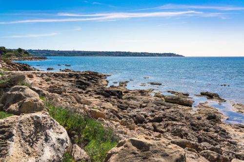 a rocky shore with the ocean in the background at Marinella in Terrauzza