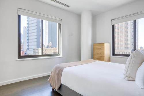 - une chambre blanche avec deux fenêtres et un lit dans l'établissement Amazing Midtown W 1BR w Gym nr Times Sq NYC-650, à New York