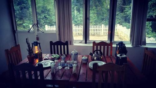 a wooden table in a dining room with windows at Riverston Nature Villa in Rattota
